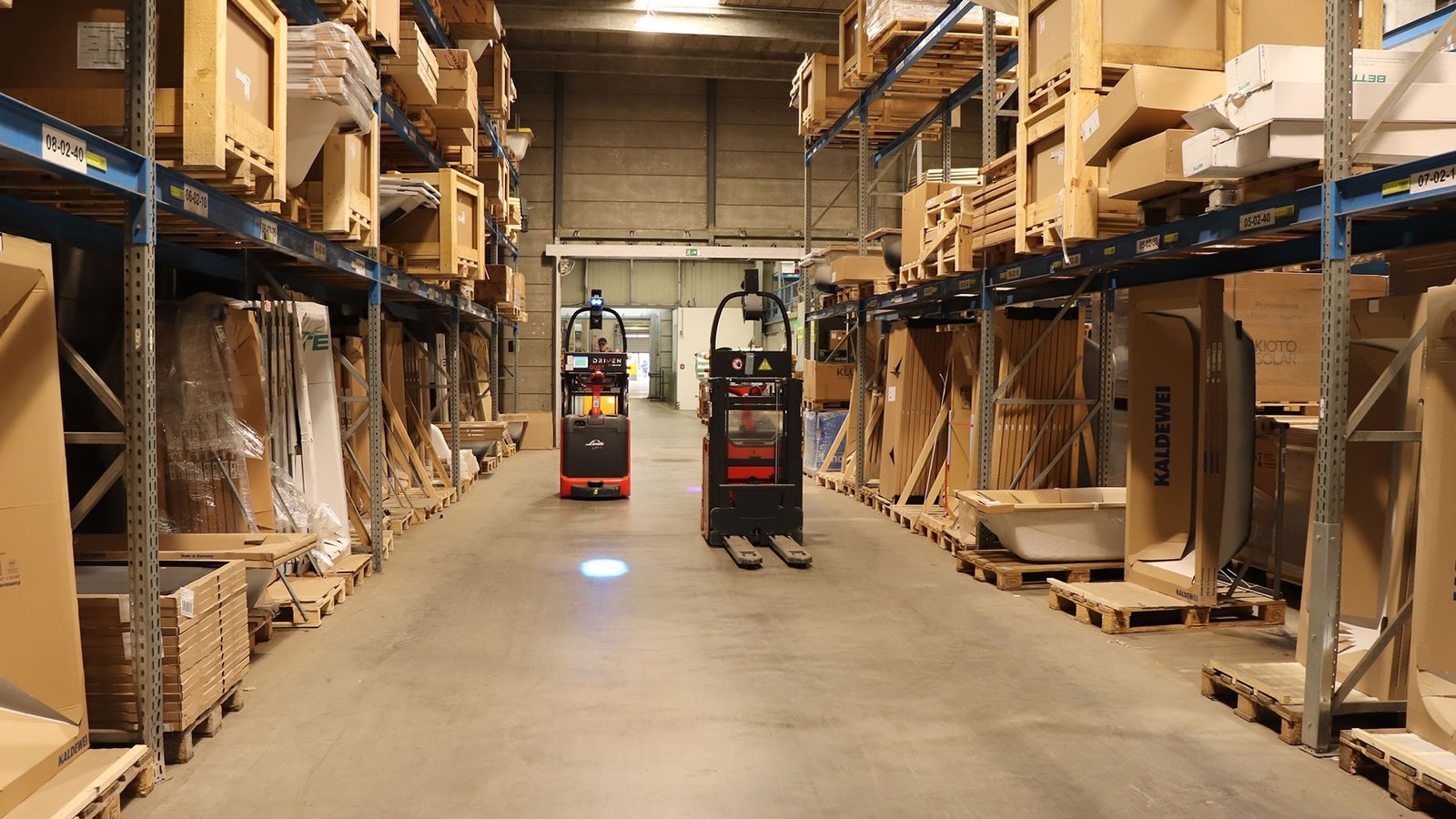 Dva Linde L-MATIC visokopodizna viljuškara rade u skladištu kompanije HOLTER između regala sa robom.