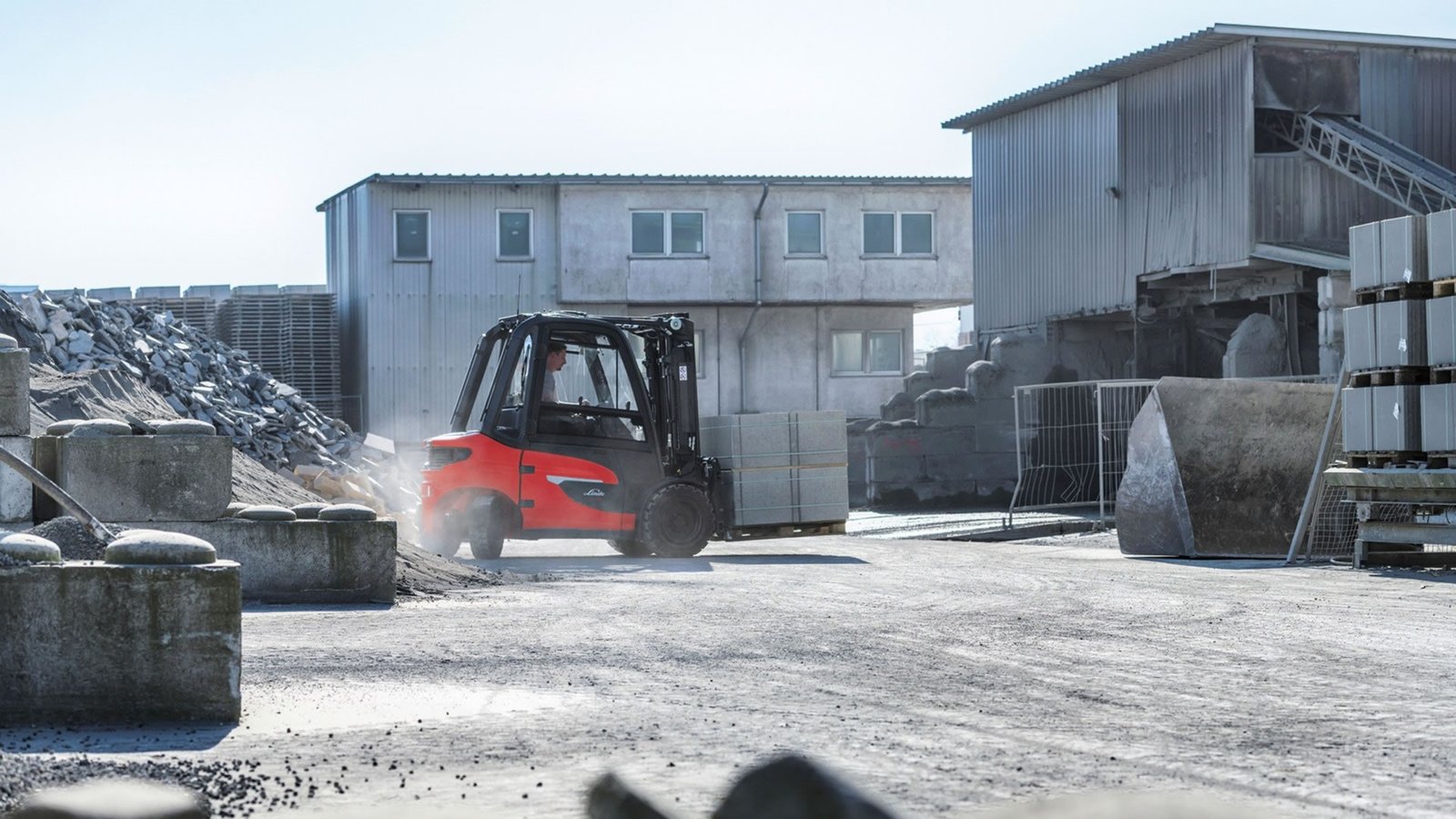 Električni viljuškar Linde X-serije u radu na otvorenom industrijskom terenu ispred magacina