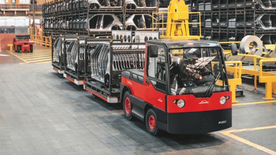 Linde tegljač vuče prikolice s metalnim delovima kroz industrijsko skladište
